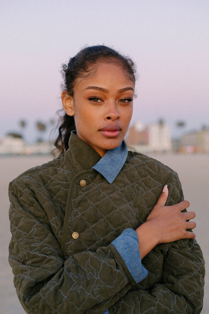 Woman looks at camera at sunset wearing quilted jacket