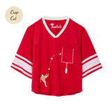 Red mesh crop-cut shirt with white stripes on the sleeves, a white V-neck, and an embroidered football design showing a player kicking a football toward a goalpost outlined around the chest pocket.