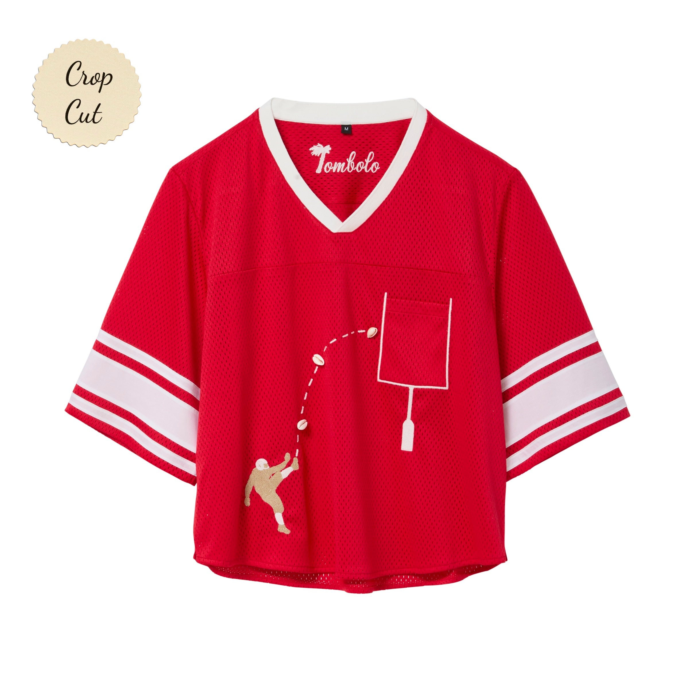 Red mesh crop-cut shirt with white stripes on the sleeves, a white V-neck, and an embroidered football design showing a player kicking a football toward a goalpost outlined around the chest pocket.