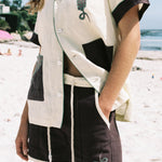 Female model wearing full 'Tombarolo' cabana set on the beach. Shirt half unbuttoned.