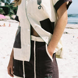 Female model wearing full 'Tombarolo' cabana set on the beach. Shirt half unbuttoned.
