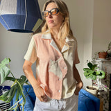 Aemilia wearing the conched out shirt and sunglasses looking out of an apartment window with a ray of light shining across her