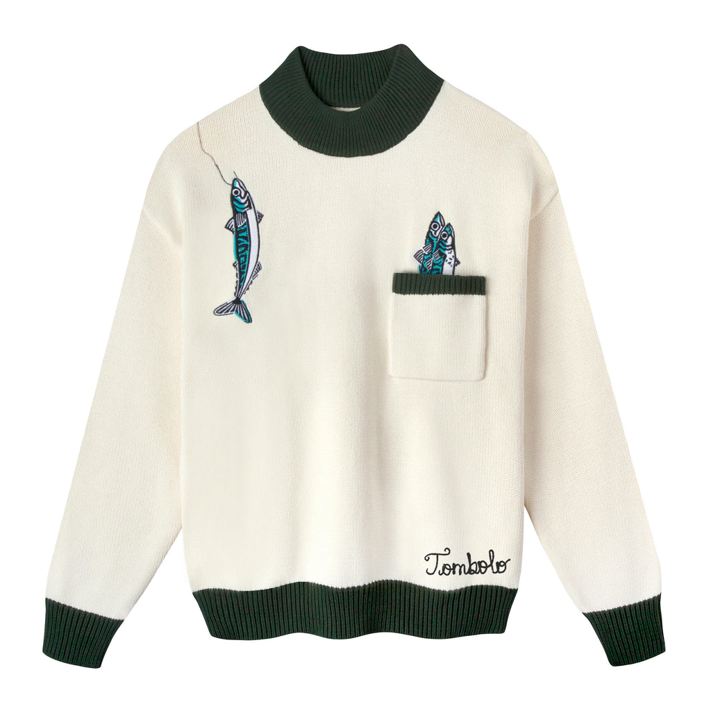 Cream knit sweater with dark green ribbed collar, cuffs, and hem. Features embroidered fish, including one hanging from a fishing line near the shoulder and two peeking out from a chest pocket. 'Tombolo' embroidered near the waist.