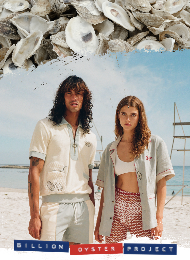 Man and woman gazing at the camera on the beach wearing Tombolo x Billion Oyster Project shirts in linen and terry cloth