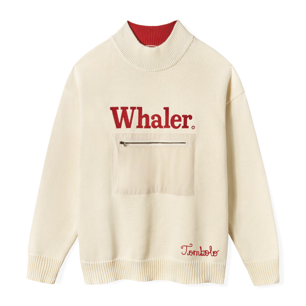 Cream knit sweater with red interior collar. Features bold red embroidered text reading 'Whaler' across the chest and a beige front zip pocket. 'Tombolo' embroidered in red near the waist. 