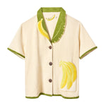 Short-sleeve cream terry cloth shirt with green trim, a green and yellow banana leaf collar, and a banana applique on the front pocket.