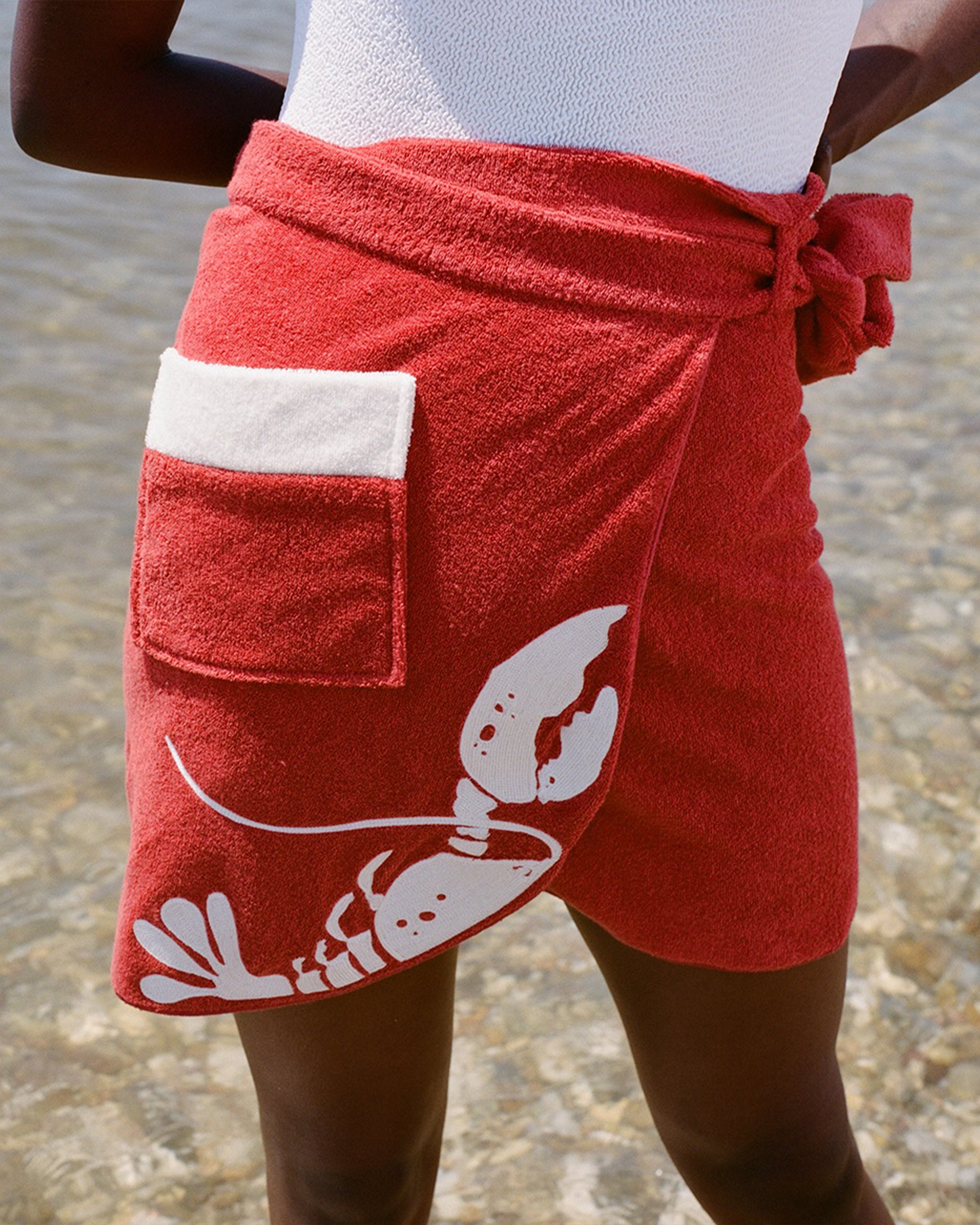 Close up of woman at beach wearing white bathing suit and red tie wrap skirt