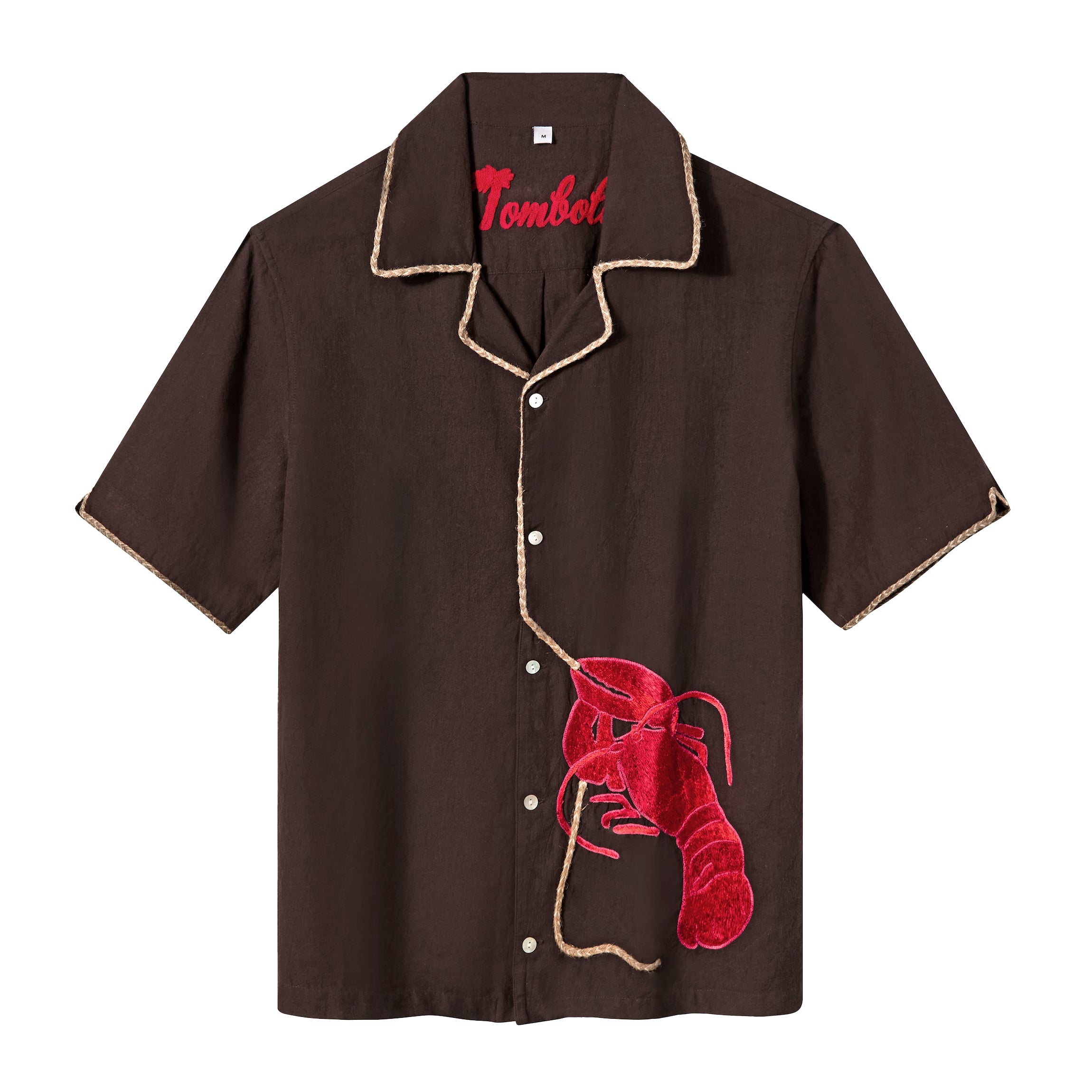 Front view of a short-sleeve, button-up shirt in dark brown with beige piping along the collar, placket, and sleeve hems. A textured red lobster applique is stitched to the lower left side, with a tan rope extending upward along the button line, mimicking the lobster's tether. The word “Tombolo” is embroidered in red inside the collar.