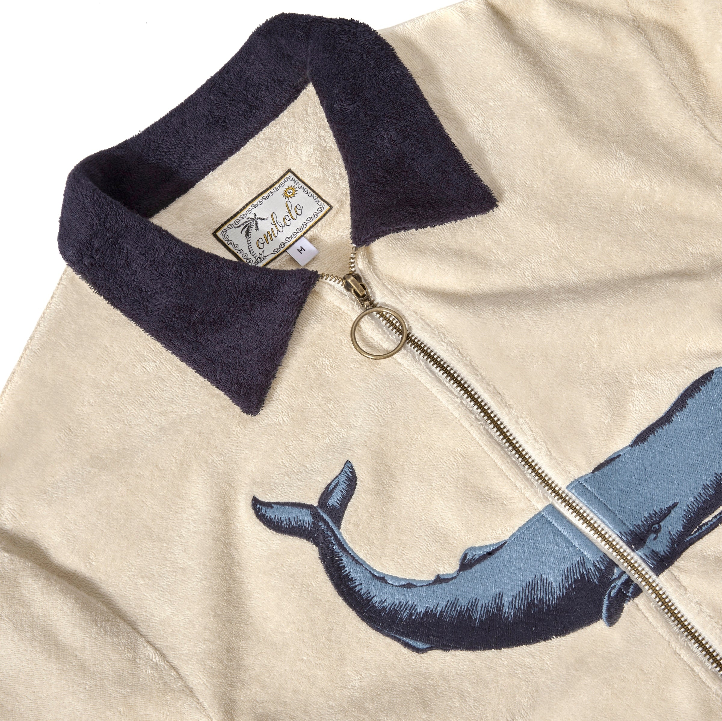Close-up of the zipper feature, dark blue collar, and interior label reading 'Tombolo.'