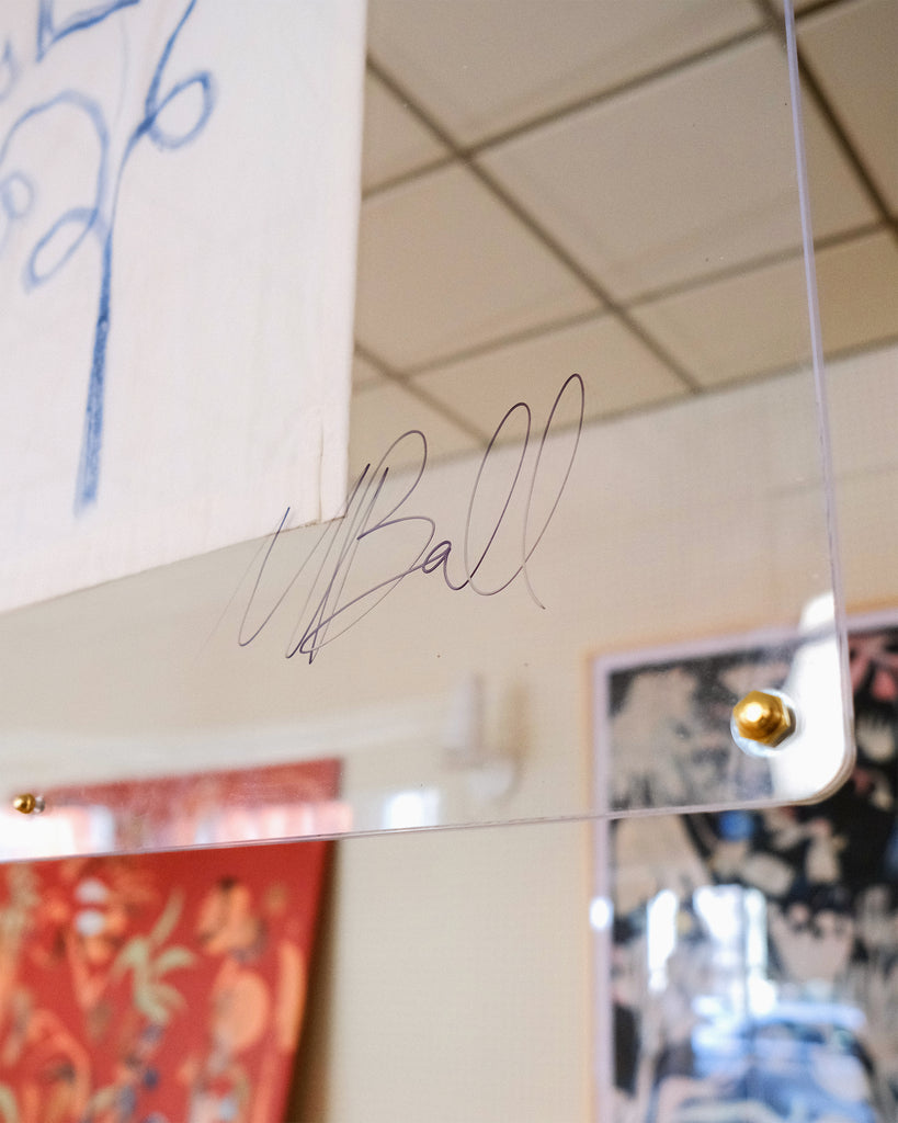 Close-up image of artist Mary Ball's signature on the glass case displaying her art.