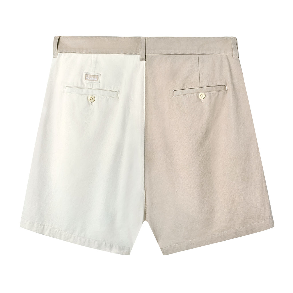 Back view of two-tone pleated shorts in beige and off-white. Features include belt loops, two welt pockets with button closures, and a small rectangular 'Tombolo' logo patch above the left pocket.