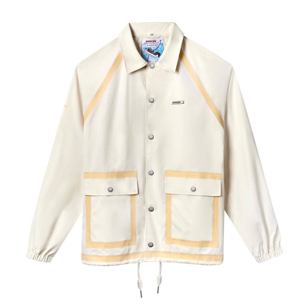 Front view of a cream hooded rain jacket with tan trim, silver snap buttons, and two large front pockets. Features the Boston Whaler logo on the left chest.