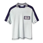 Light blue cotton mesh short-sleeve shirt with navy shoulder panels and a striped ribbed collar. Features a navy chest pocket with white 'Boston Whaler' embroidery and navy contrast stitching on the cuffs and hem. 