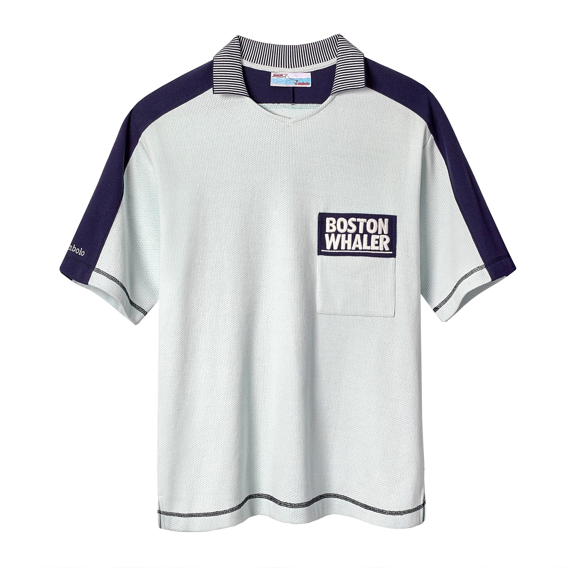 Light blue cotton mesh short-sleeve shirt with navy shoulder panels and a striped ribbed collar. Features a navy chest pocket with white 'Boston Whaler' embroidery and navy contrast stitching on the cuffs and hem. 