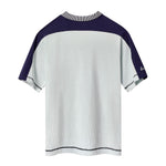 Backside of light blue cotton mesh short-sleeve shirt with navy shoulder panels and a striped ribbed collar. 