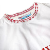 Close-up of the red and white knit collar on a white t-shirt, featuring a woven pattern and interior label with Tombolo and Boston Whaler branding.