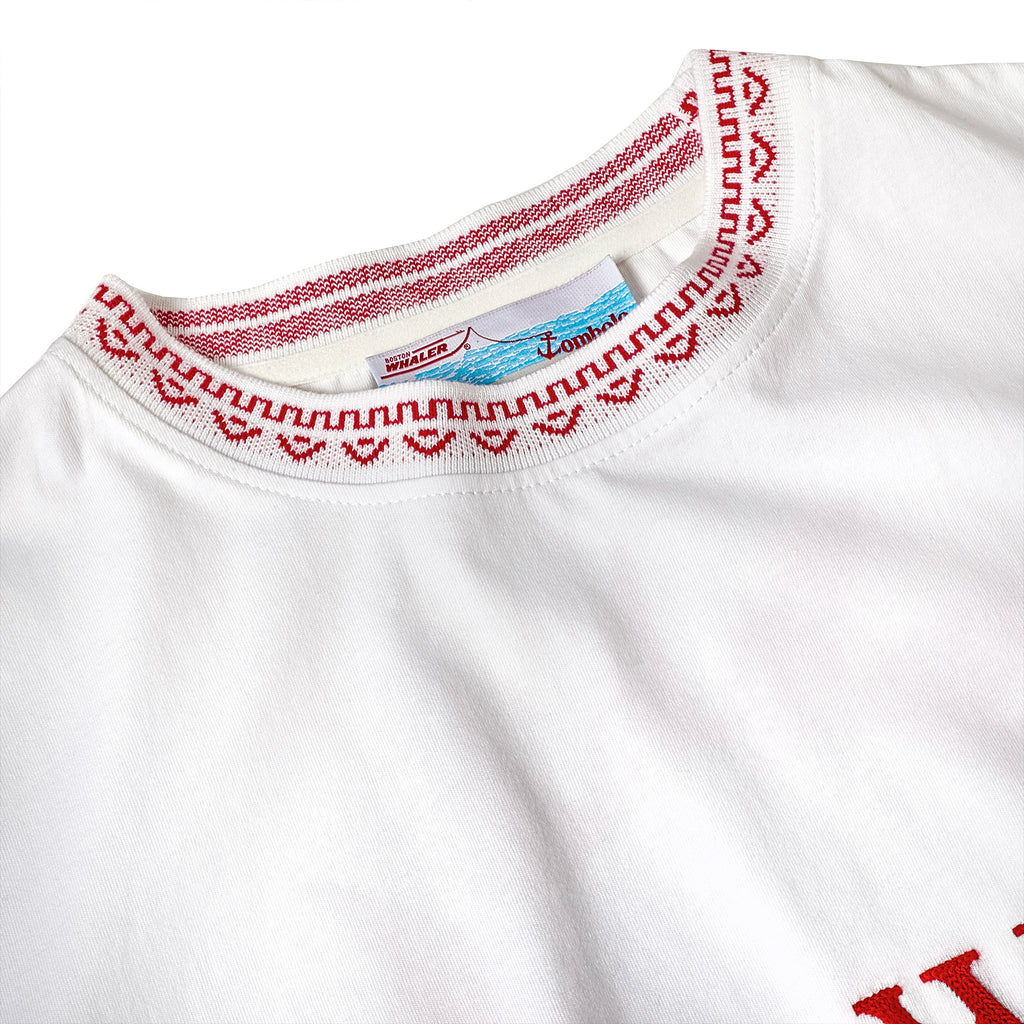 Close-up of the red and white knit collar on a white t-shirt, featuring a woven pattern and interior label with Tombolo and Boston Whaler branding.