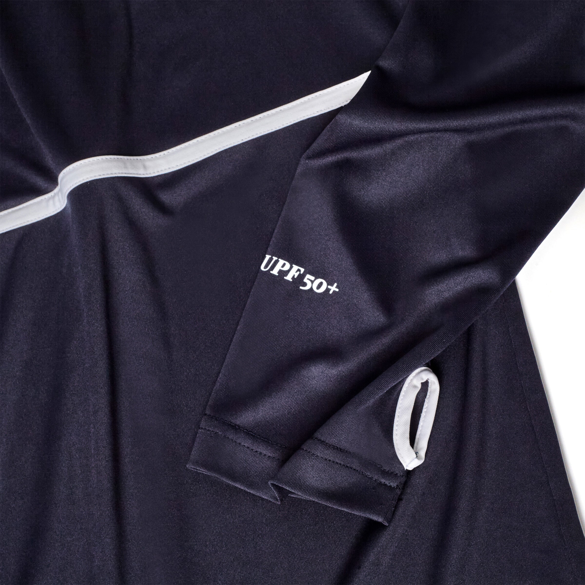 Close-up of a navy sun shirt sleeve featuring white piping, UPF 50+ text, and a white-trimmed thumbhole.