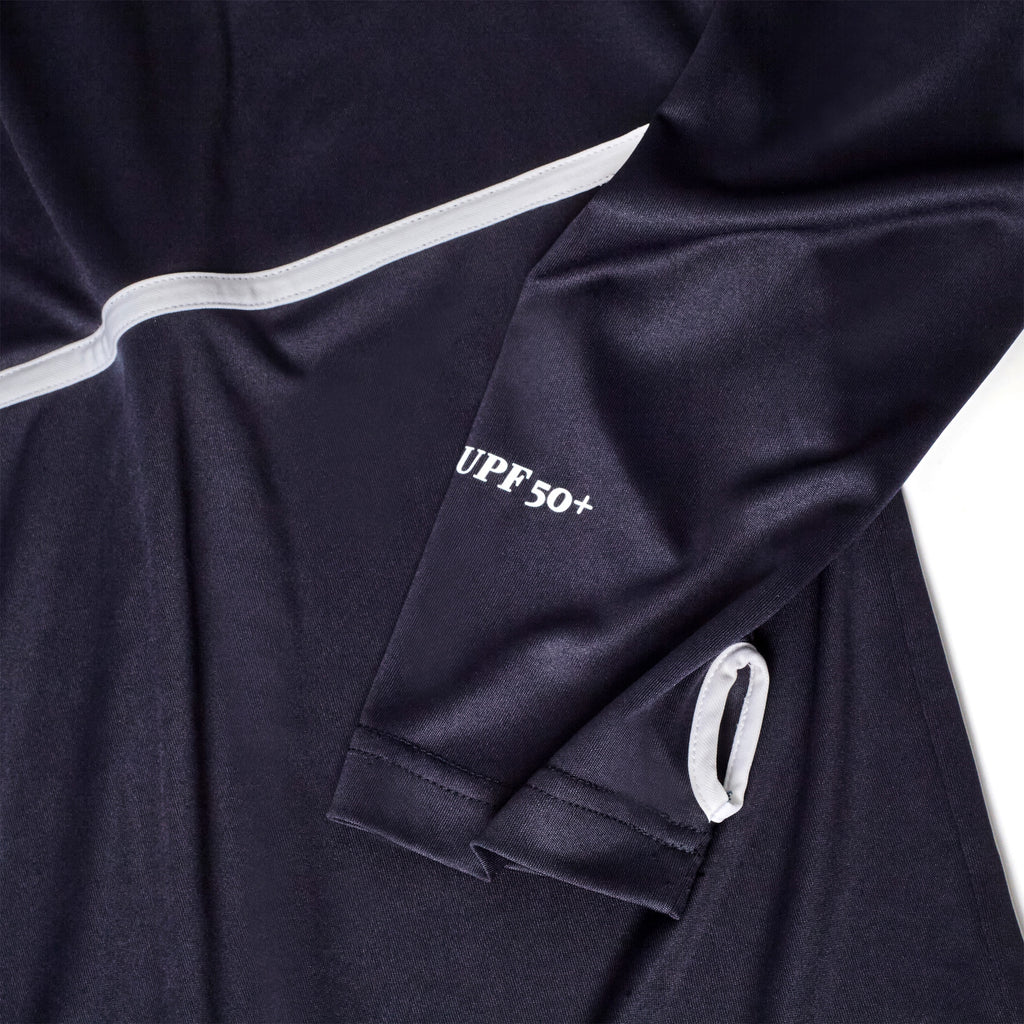 Close-up of a navy sun shirt sleeve featuring white piping, UPF 50+ text, and a white-trimmed thumbhole.