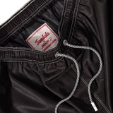 Close up product image of the 'boston whaler' swim trunks' interior label and metal eyelet stoppers on white and black twist drawstrings.