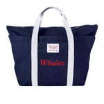 Navy canvas tote bag with white handles and a front pocket. Red embroidered text on the pocket reads ‘Whaler.’ A small white label above the pocket reads ‘Wm. J. Mills & Co. Sailmakers, Greenport, N.Y.’