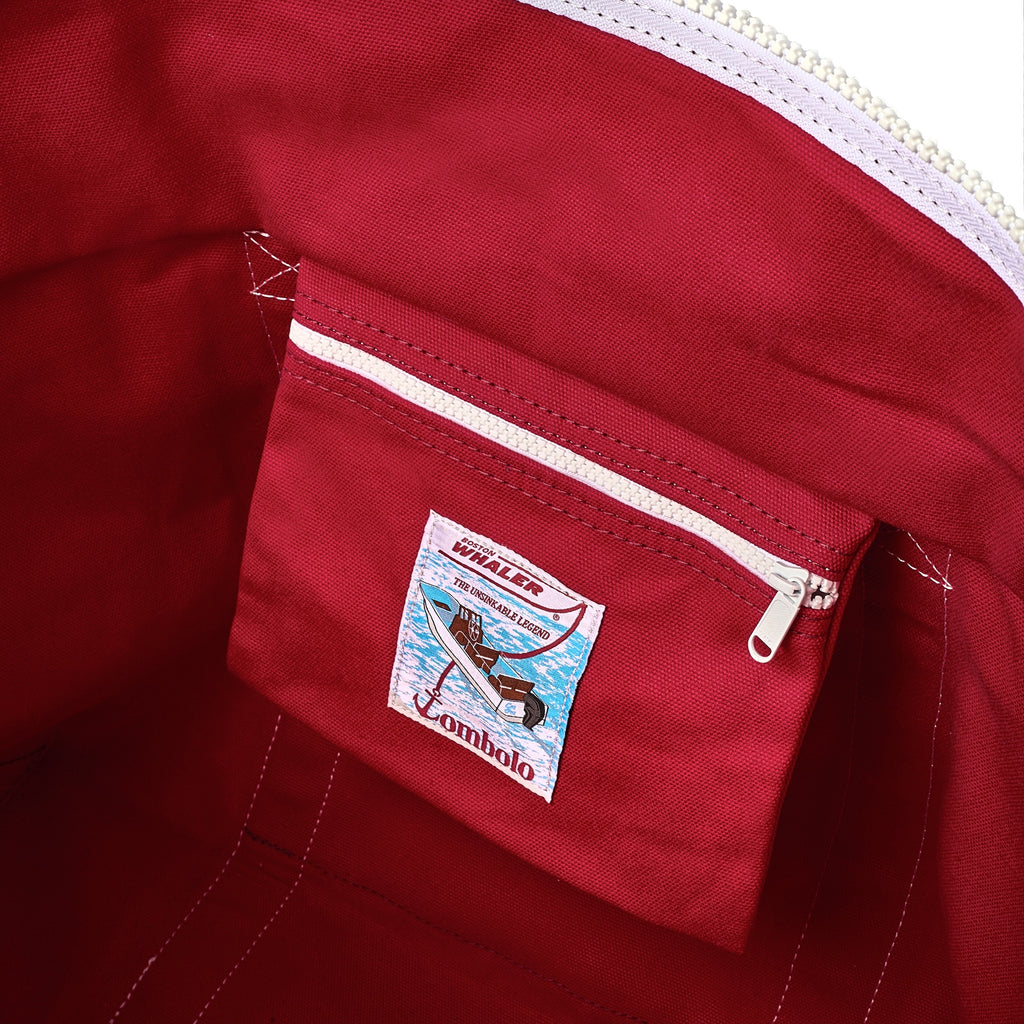 Close-up of canvas tote interior pocket, featuring a 'Boston Whaler' and 'Tombolo' co-branded label.