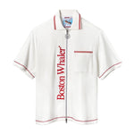 White short-sleeve terry cloth zip-up shirt with red vertical 'Boston Whaler' text, red contrast stitching, a front chest pocket with red stripes, and a ship wheel zipper pull.