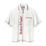 White short-sleeve terry cloth zip-up shirt with red vertical 'Boston Whaler' text, red contrast stitching, a front chest pocket with red stripes, and a ship wheel zipper pull.