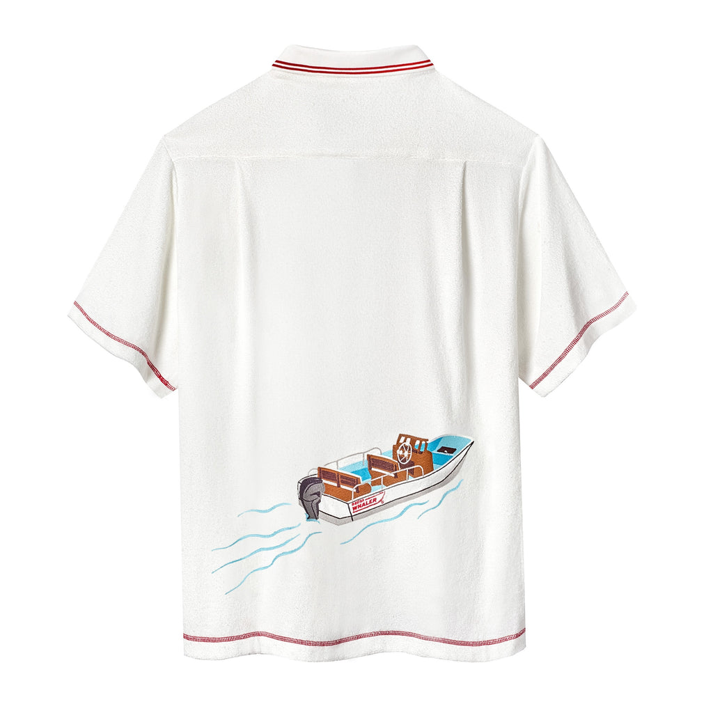 Backside of white short-sleeve terry cloth zip-up shirt with  red contrast stitching and a boat illustration across the back.