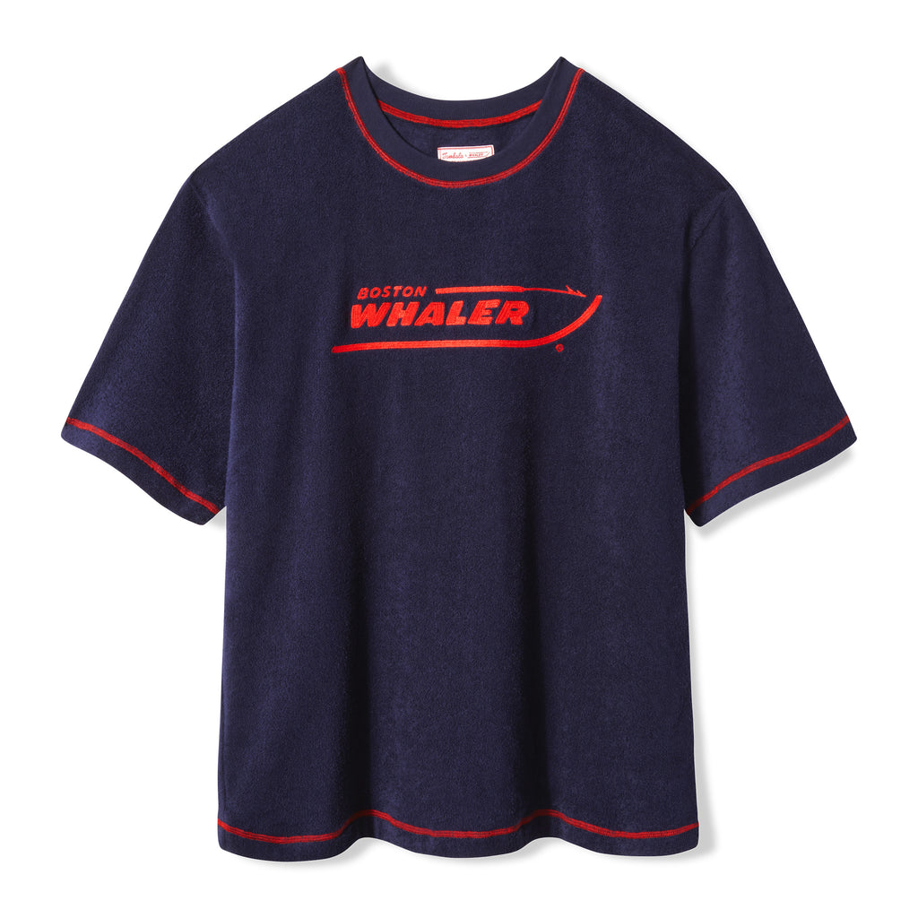 Front-facing product image of the 'Boston Whaler' Souvenir Terry Tee made of 100% organic terry cloth, chain-stitched Boston Whaler logo across chest, red, contrast overlock stitch on neckline, cuffs and bottom sweep, boxy, nostalgic fit, and custom 'Tombolo & Boston Whaler' woven interior label secured with zig-zag sail stitch.