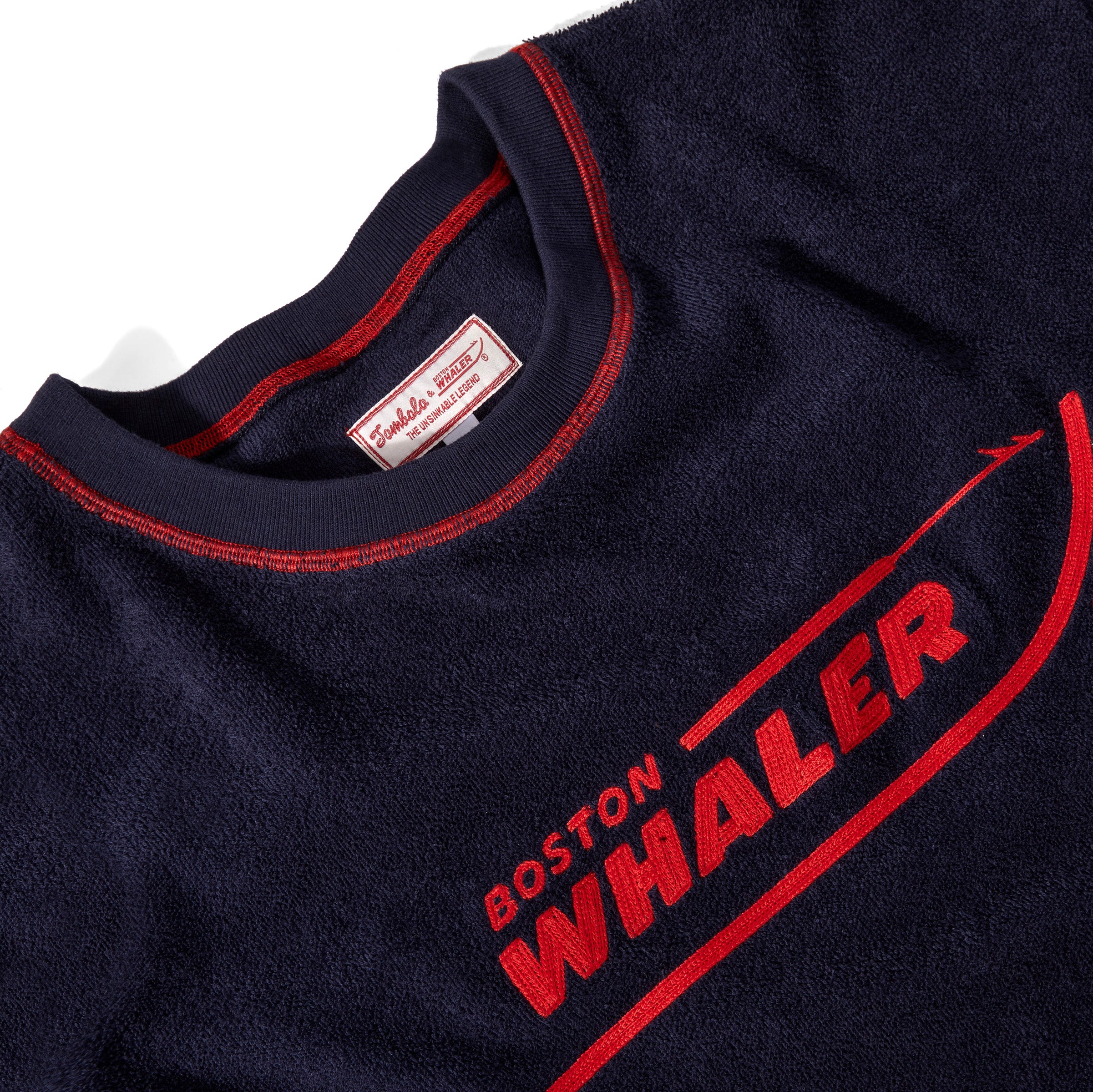 Close-up product image of the 'boston whaler souvenir terry tee that showcases the interior label tag, and Whaler logo on the front of the shirt.