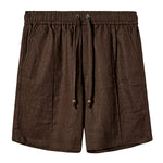 A pair of dark brown linen shorts with a relaxed fit. They feature an elastic waistband with a matching drawstring that includes wooden bead tips. The shorts have two side pockets and subtle stitching details throughout, offering a breezy, casual look.