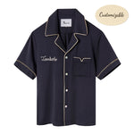 Navy short-sleeved Tencel twill shirt with a relaxed collar, beige piping, and Agoya shell buttons, customizable with embroidery.