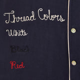 Close up of embroidery reading 'Thread Colors: White, Black, Red.'