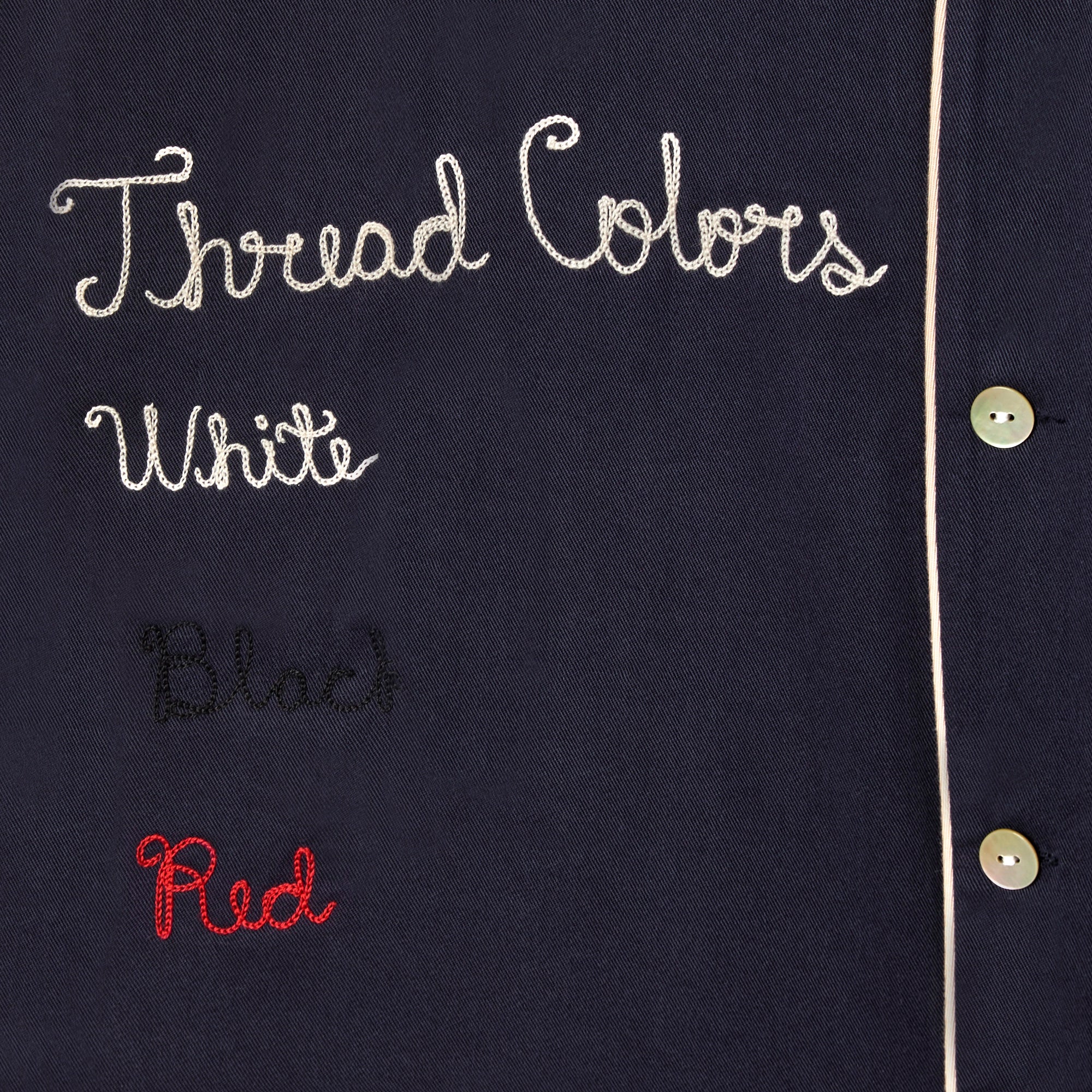 Close up of embroidery reading 'Thread Colors: White, Black, Red.'