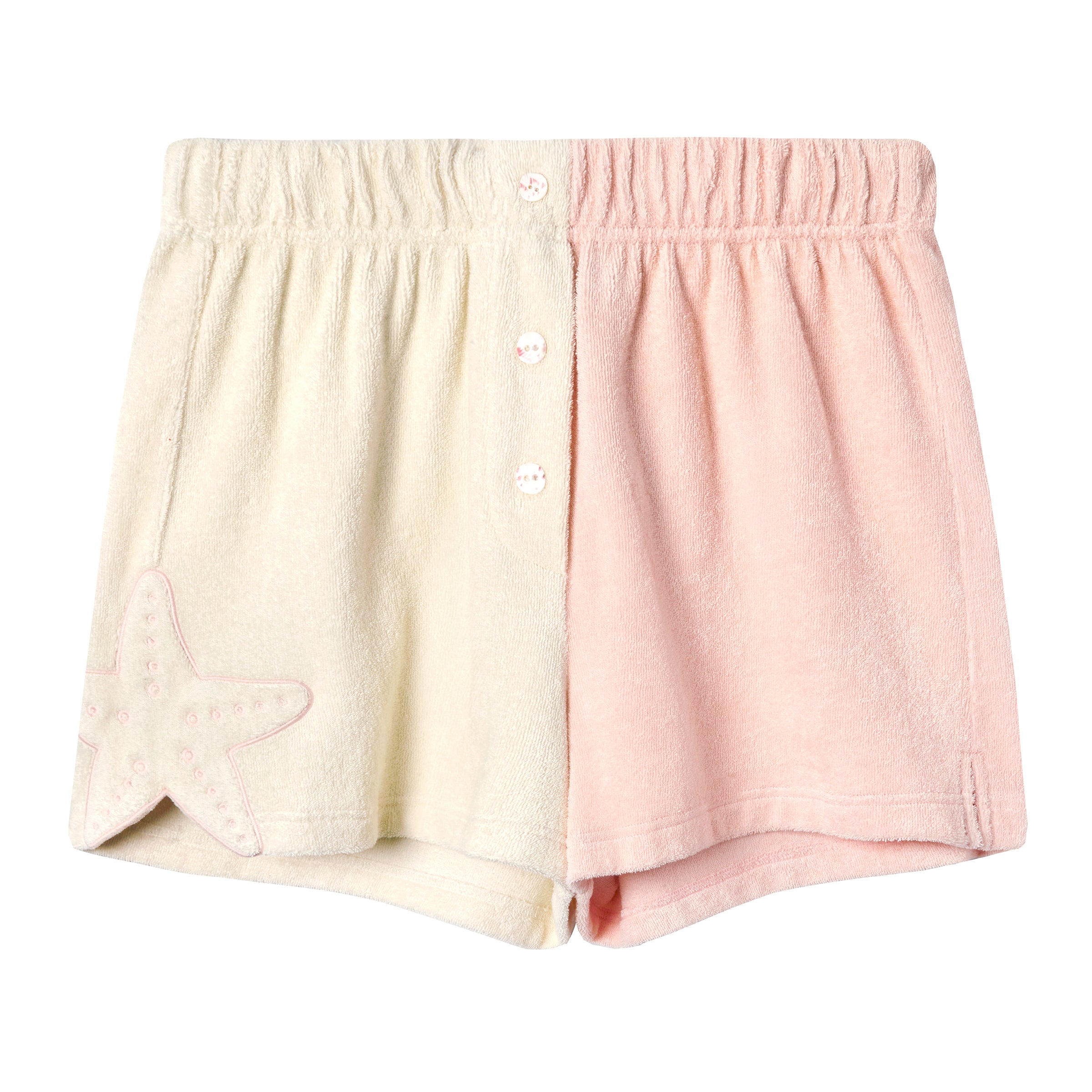 Two-tone terrycloth shorts featuring a beige left side and soft pink right side, with a pink embroidered starfish on the left hem and decorative flower-shaped buttons down the center front. The waistband is elastic and gathered for comfort.