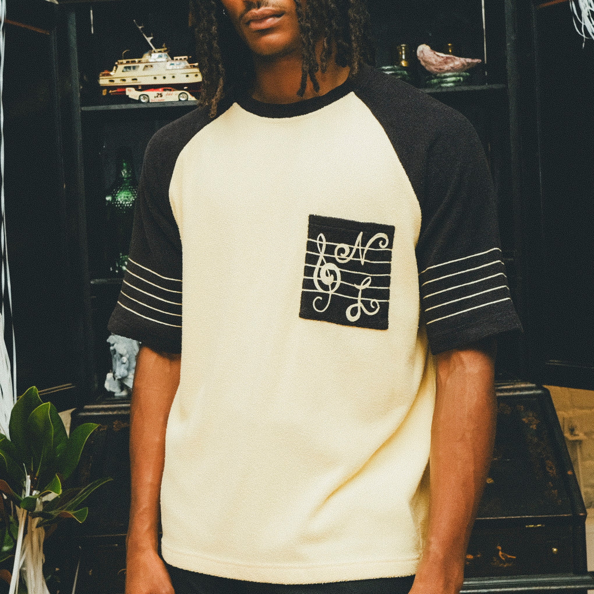 Model wearing cream and black raglan terry shirt with SNL-embroidered chest pocket.