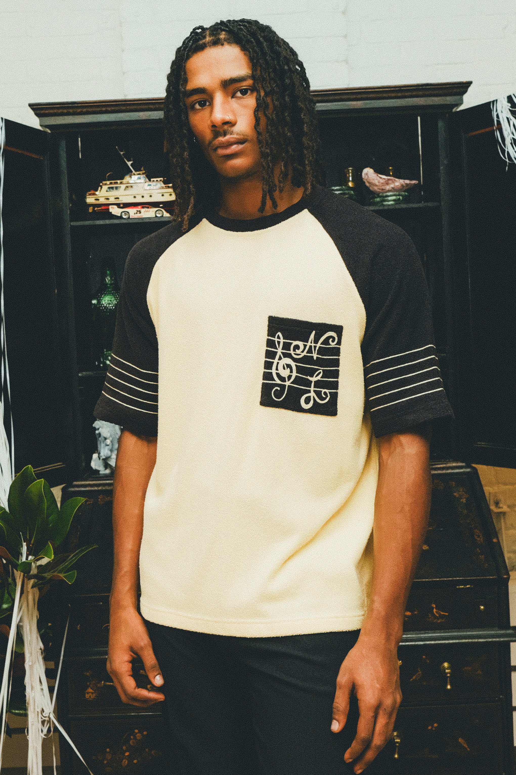 Model wearing cream and black raglan terry shirt with SNL-embroidered chest pocket.