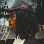 Man wearing a cap with 'Live from New York' text on the left temple.
