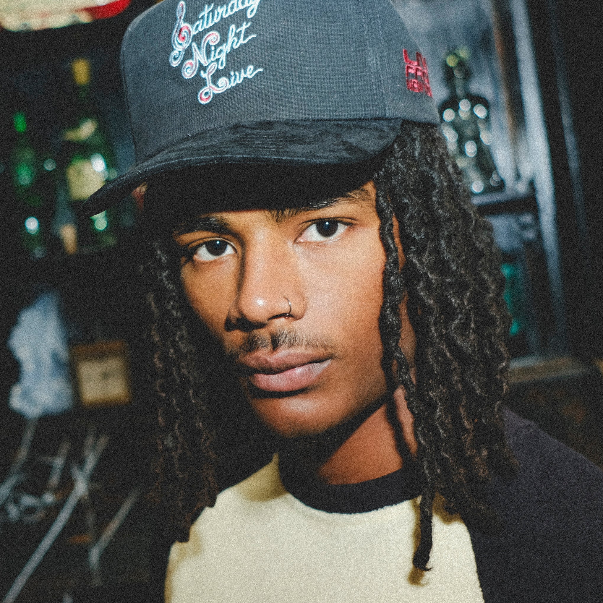 Model wearing a black cap with 'Saturday Night Live' embroidery.
