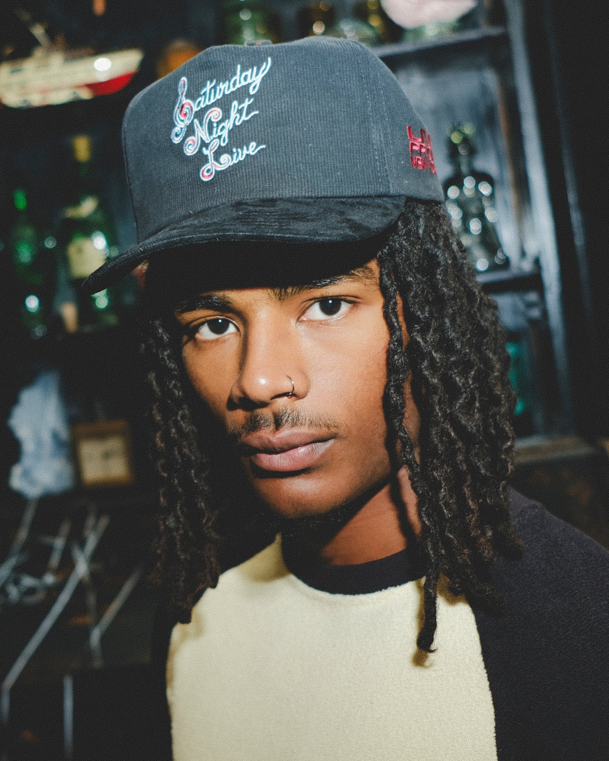 Model wearing a black cap with 'Saturday Night Live' embroidery.