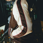 Brown and cream souvenir jacket with red trim on a dark background