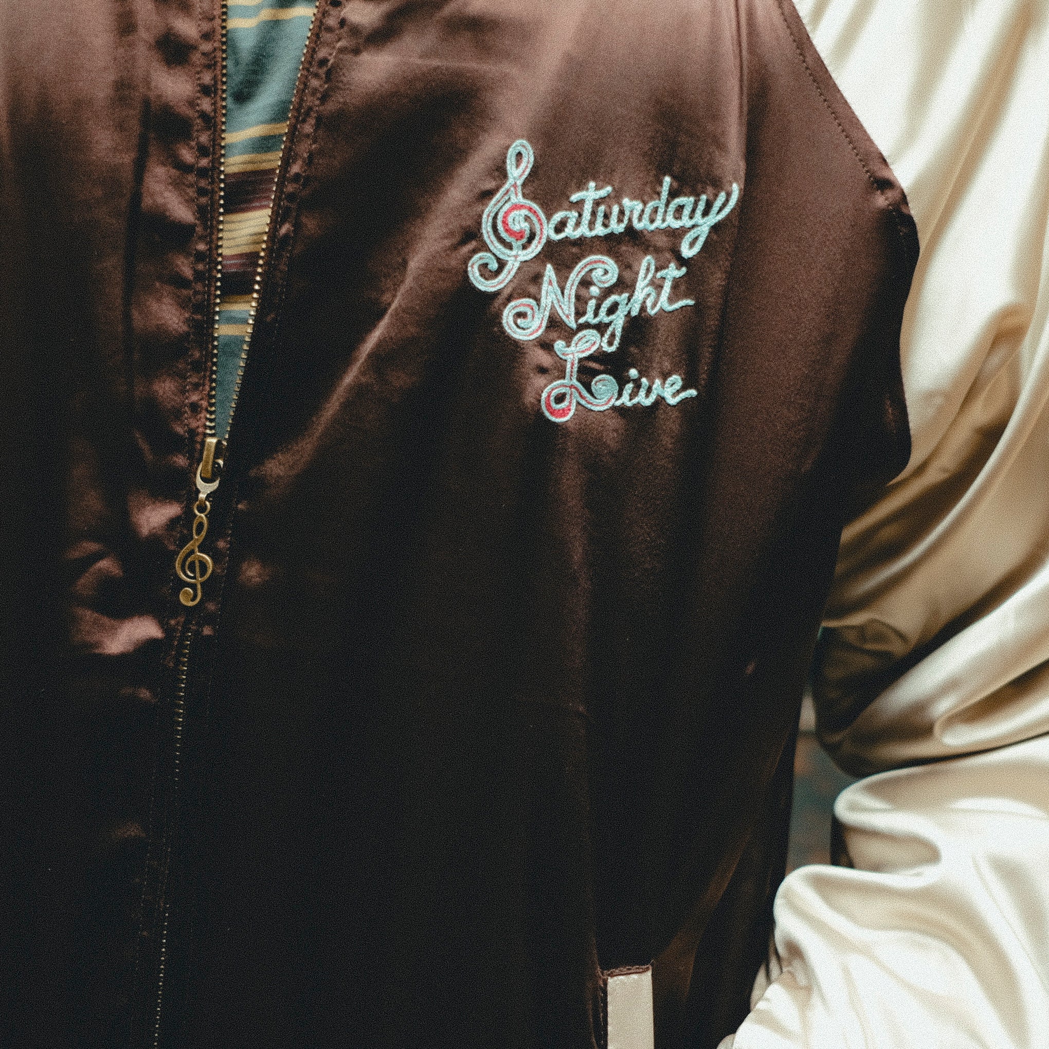 Brown jacket with 'Saturday Night Live' embroidery on chest.