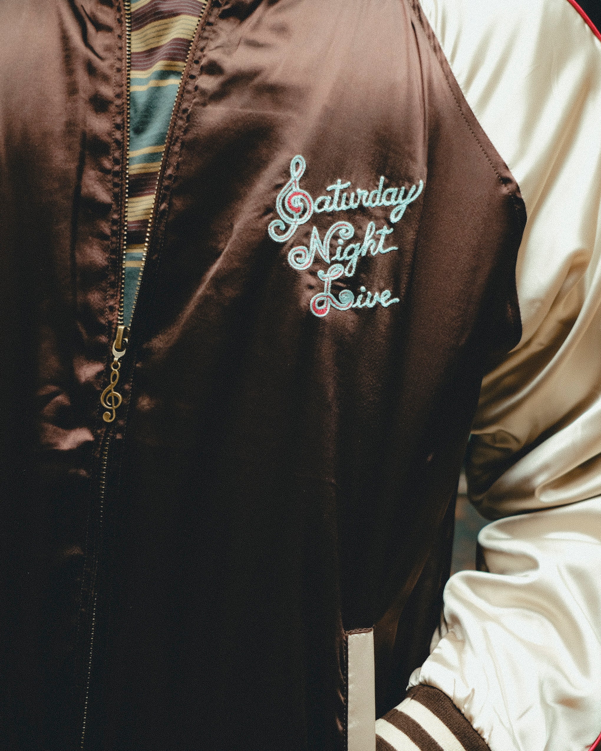 Brown jacket with 'Saturday Night Live' embroidery on chest.