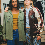 Two models standing together, wearing the SNL Long Sleeve 1976 shirt and the Souvenir Jacket. 