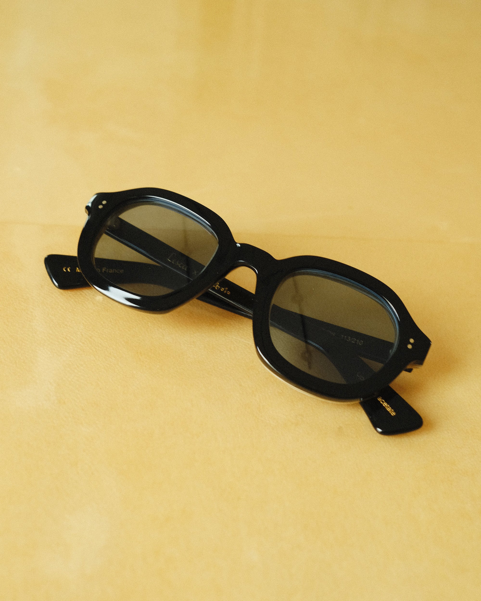 black thick sunglasses with blue frame against a yellow background