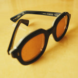 close up of black framed sunglasses with coral lenses that says 'LARGO LIMITED EDITION 113/210' in interior