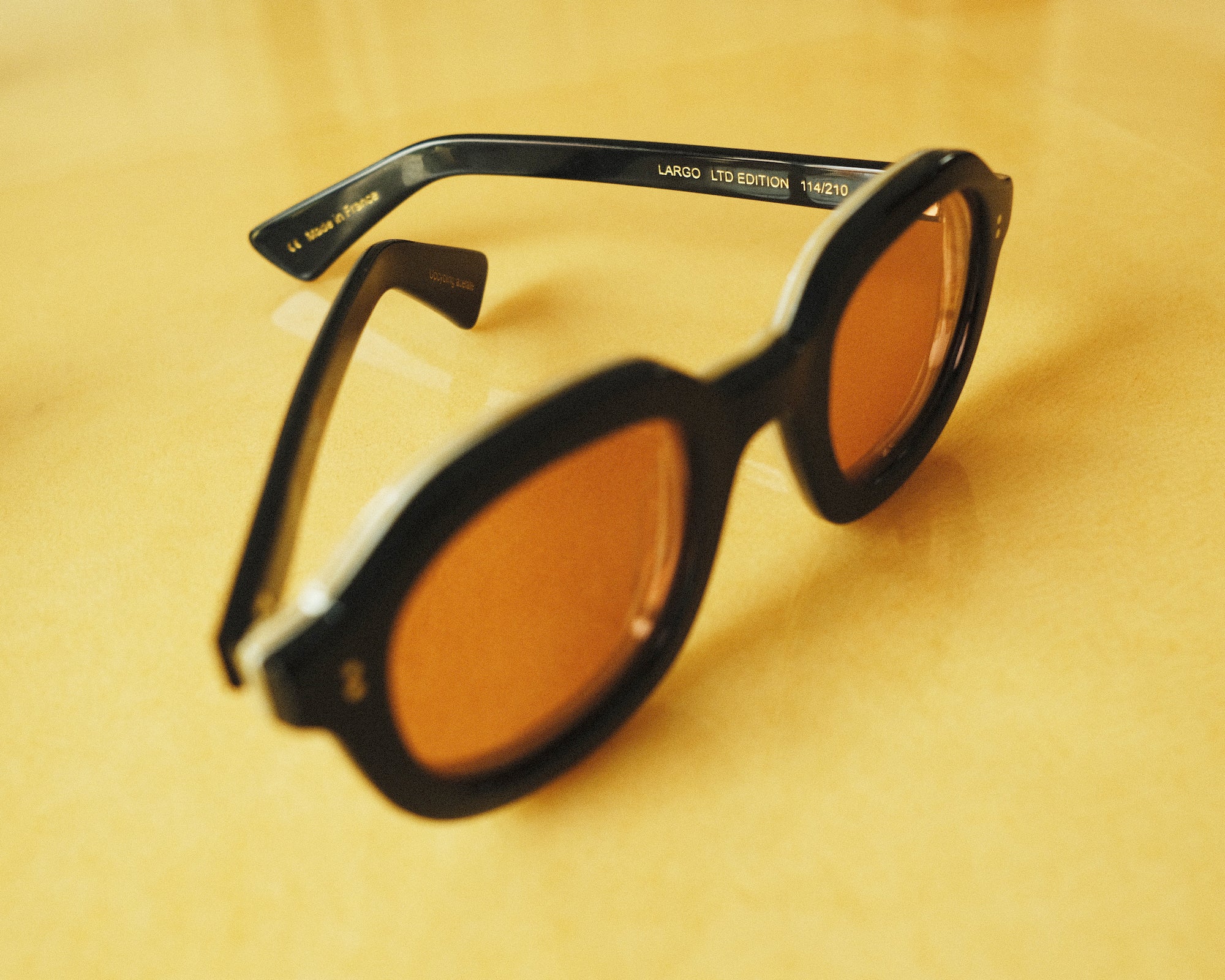 close up of black framed sunglasses with coral lenses that says 'LARGO LIMITED EDITION 113/210' in interior