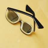 interior of thick sunglasses with blue frame against a yellow background; interior of frames are beige 