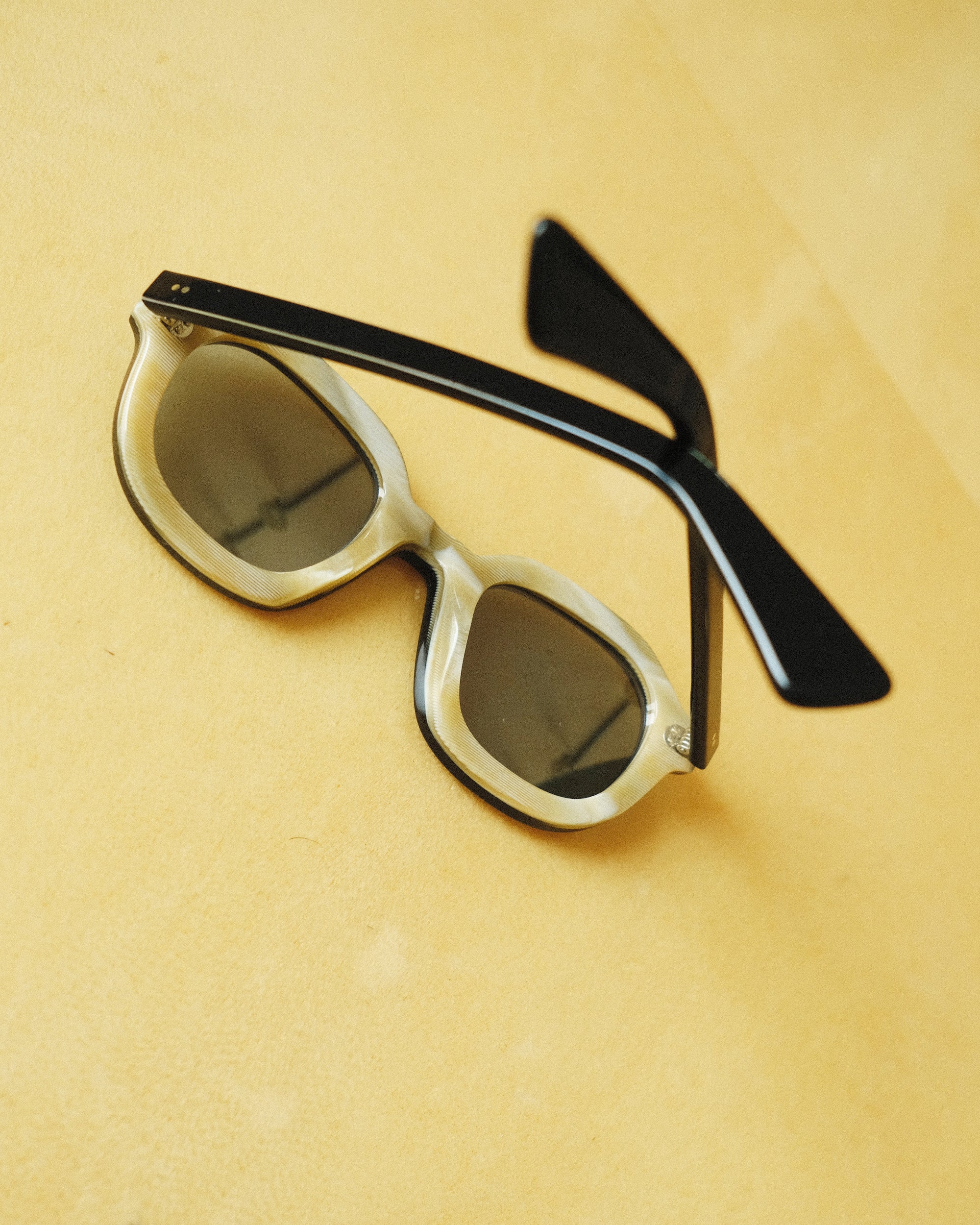 interior of thick sunglasses with blue frame against a yellow background; interior of frames are beige 